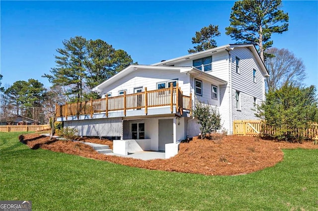 rear view of property featuring a deck, a lawn, and fence