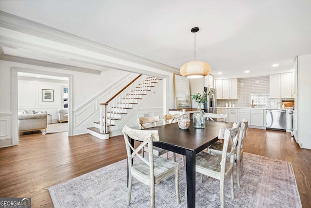 dining area with stairs, ornamental molding, and a decorative wall