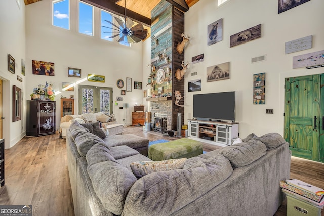 living area with ceiling fan, a fireplace, visible vents, french doors, and wood-type flooring