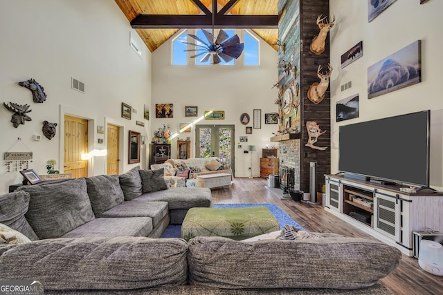 living room featuring ceiling fan, visible vents, wood finished floors, and a stone fireplace