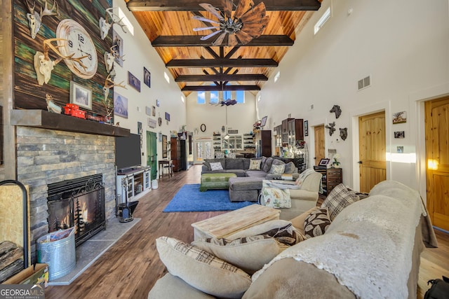 living area with wooden ceiling, wood finished floors, visible vents, beam ceiling, and a glass covered fireplace