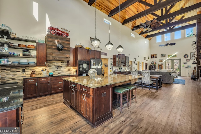 kitchen with ceiling fan, dark wood finished floors, freestanding refrigerator, and a kitchen breakfast bar