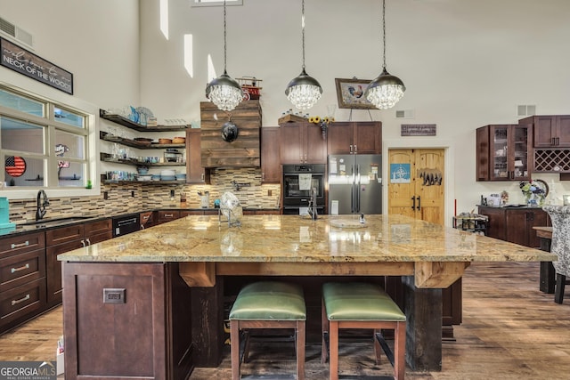 kitchen with dobule oven black, a high ceiling, a sink, and freestanding refrigerator