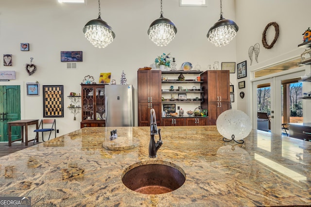 kitchen featuring freestanding refrigerator, decorative light fixtures, a sink, and open shelves