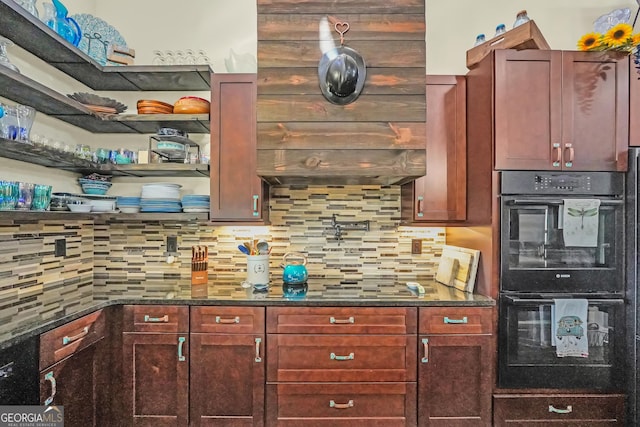 kitchen featuring dark stone counters, black appliances, reddish brown cabinets, and decorative backsplash