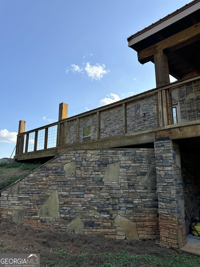 rear view of house with cooling unit, stone siding, a yard, and a wooden deck