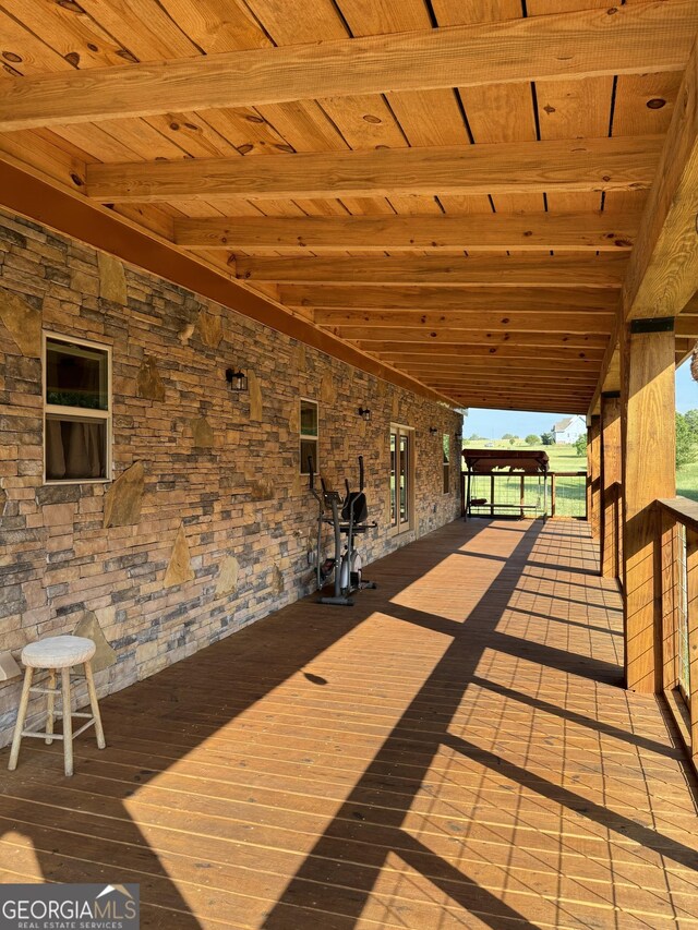 rear view of house featuring stone siding, a lawn, and a deck