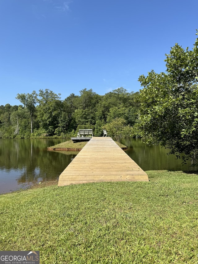 view of dock with a water view and a yard