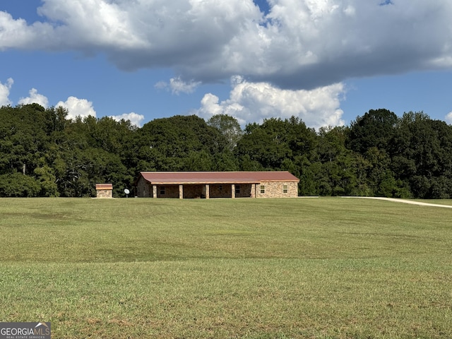 view of front of property featuring a view of trees and a front lawn