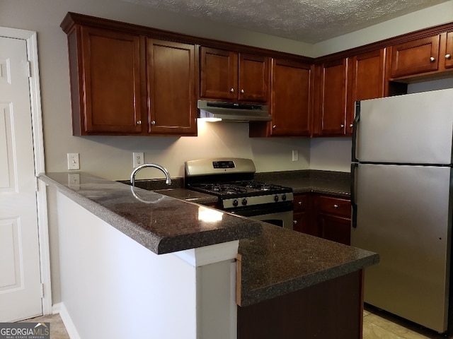 kitchen with a peninsula, a sink, stainless steel appliances, under cabinet range hood, and a textured ceiling