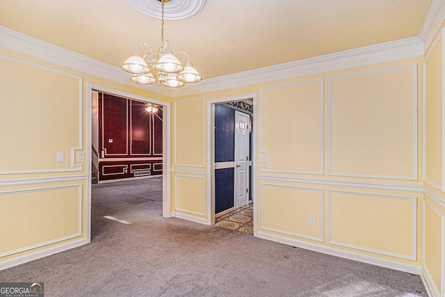 spare room with ornamental molding, a textured ceiling, carpet flooring, a chandelier, and a decorative wall