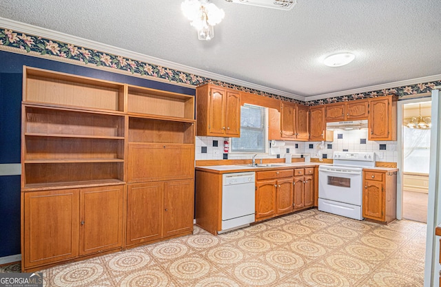 kitchen featuring under cabinet range hood, white appliances, a sink, light countertops, and brown cabinetry