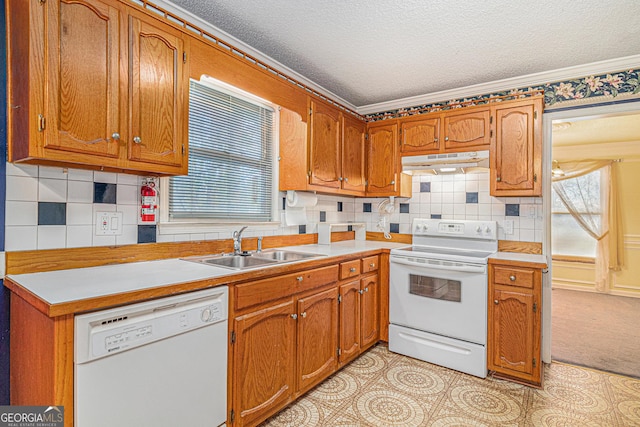 kitchen with crown molding, a sink, a textured ceiling, white appliances, and under cabinet range hood