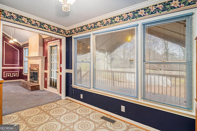 carpeted spare room with a textured ceiling, a fireplace, visible vents, and baseboards