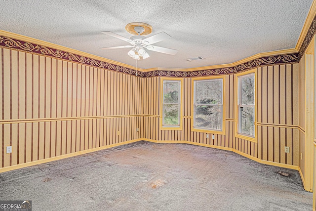 carpeted empty room with wallpapered walls, ceiling fan, visible vents, and a textured ceiling