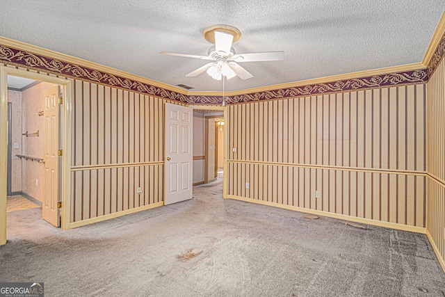 carpeted empty room with wallpapered walls, baseboards, ceiling fan, crown molding, and a textured ceiling