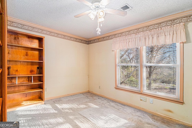 carpeted spare room with a textured ceiling, ceiling fan, plenty of natural light, and visible vents