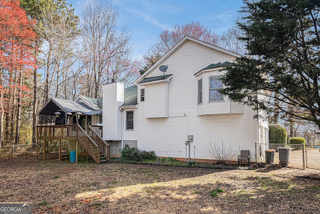 view of home's exterior featuring a chimney, a gate, stairs, fence, and a deck