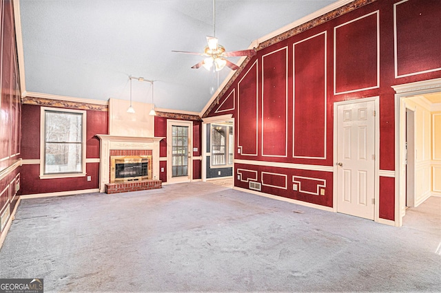 unfurnished living room with a decorative wall, carpet floors, a ceiling fan, vaulted ceiling, and a brick fireplace