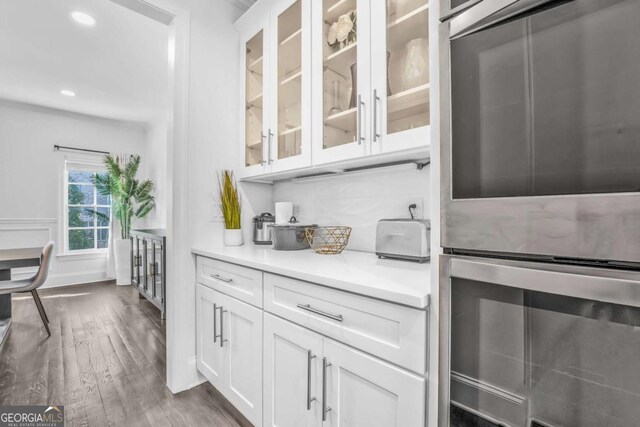 2850 Stonehall Ct SE, Smyrna, GA 30339 - kitchen with white cabinetry, light countertops, backsplash, dark wood finished floors, and glass insert cabinets