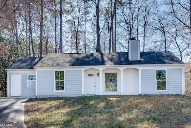 ranch-style house featuring a front yard, roof with shingles, and a chimney