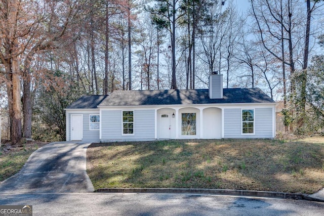 ranch-style home with a chimney and a front lawn