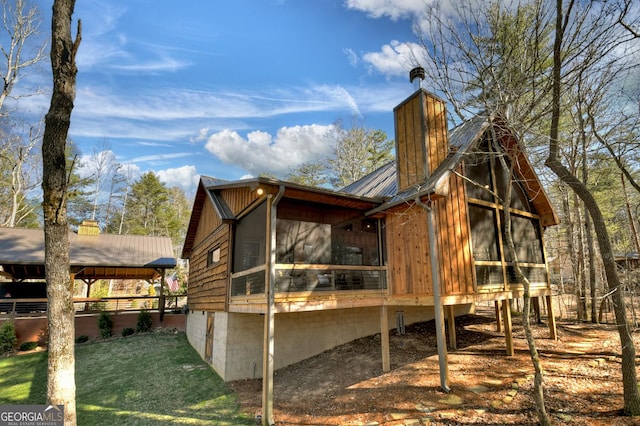 back of property with a sunroom, a yard, a chimney, and metal roof