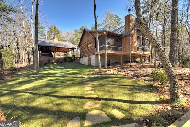 rear view of property with a sunroom, a yard, and a chimney