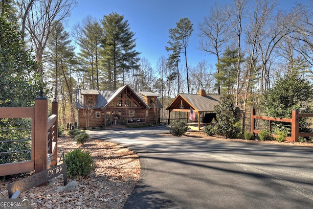 view of front of property featuring metal roof, aphalt driveway, and fence