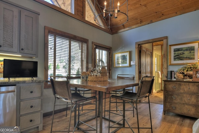 dining space with wood ceiling, an inviting chandelier, light wood-style flooring, and high vaulted ceiling