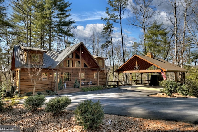 rustic home with a detached carport, metal roof, and driveway