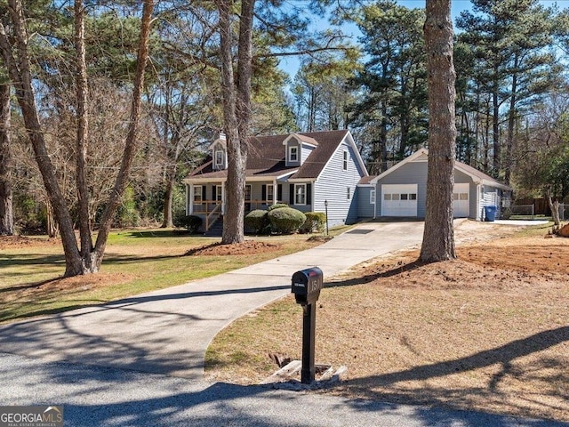 cape cod home with a front yard, a detached garage, and an outdoor structure