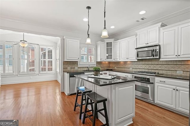 kitchen featuring a breakfast bar area, stainless steel appliances, backsplash, white cabinetry, and a sink