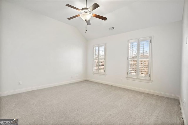 empty room featuring light colored carpet, visible vents, lofted ceiling, and baseboards