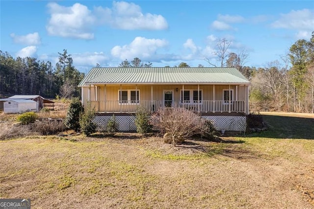 back of house with covered porch, a yard, metal roof, and board and batten siding