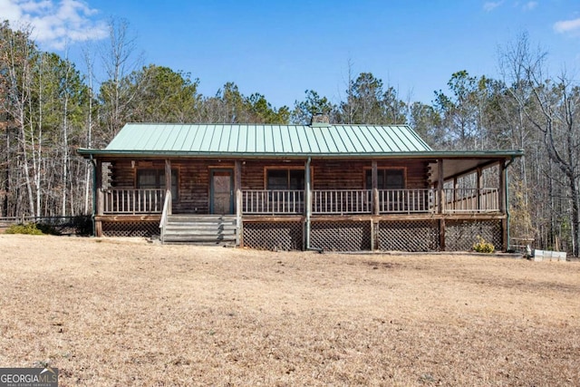 view of front of home with covered porch, metal roof, a standing seam roof, and log siding