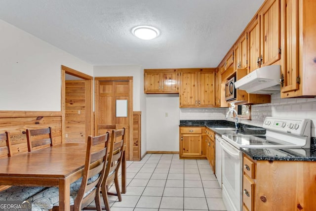 kitchen featuring light tile patterned floors, electric range, stainless steel microwave, under cabinet range hood, and a sink