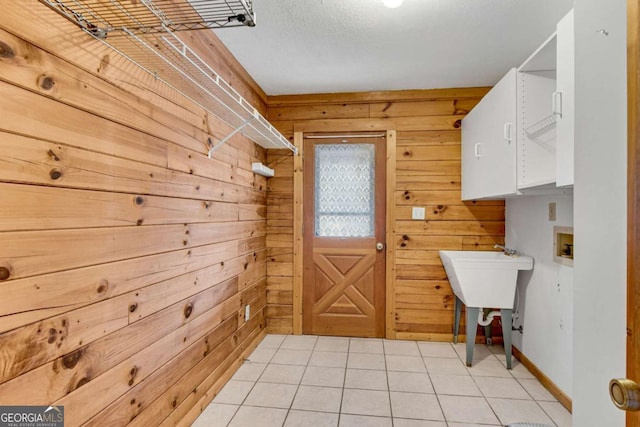 washroom featuring light tile patterned floors, hookup for a washing machine, cabinet space, and wooden walls