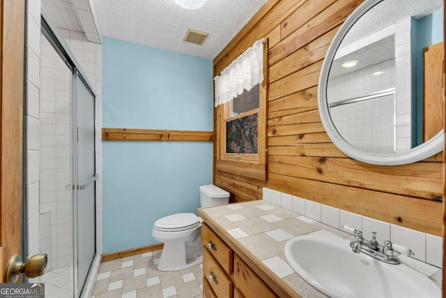 bathroom featuring wood walls, visible vents, a textured ceiling, and a stall shower