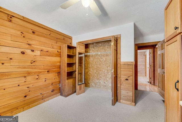 bedroom featuring a textured ceiling, carpet floors, wood walls, and a closet