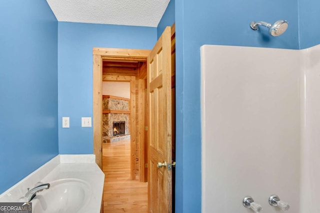 bathroom with a textured ceiling, a fireplace, and a sink