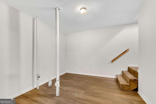 below grade area featuring stairs, baseboards, and wood finished floors