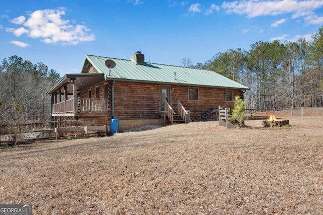 view of side of home with entry steps, a chimney, fence, and metal roof