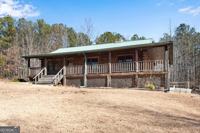 log home featuring covered porch, a chimney, log siding, and metal roof