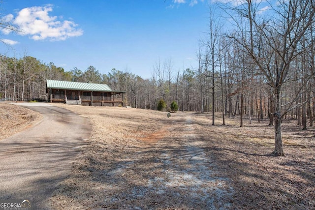 view of road with aphalt driveway and a view of trees