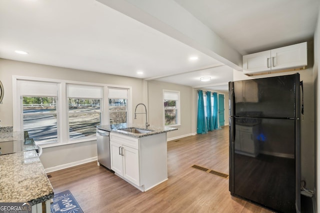 kitchen featuring a sink, visible vents, white cabinetry, stainless steel dishwasher, and freestanding refrigerator