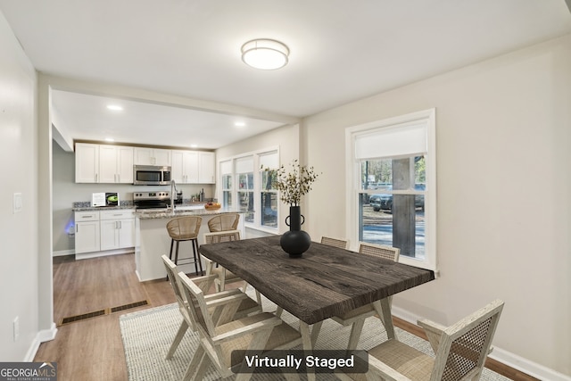 dining space featuring a healthy amount of sunlight, light wood-style flooring, and baseboards