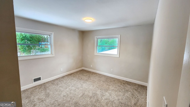 spare room featuring carpet, visible vents, and baseboards