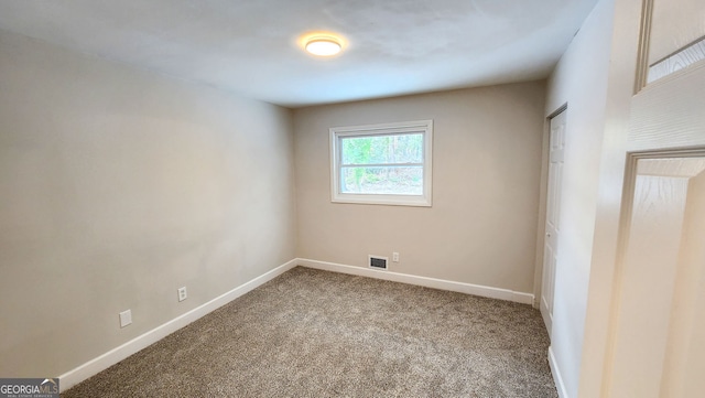 unfurnished room with carpet, visible vents, and baseboards