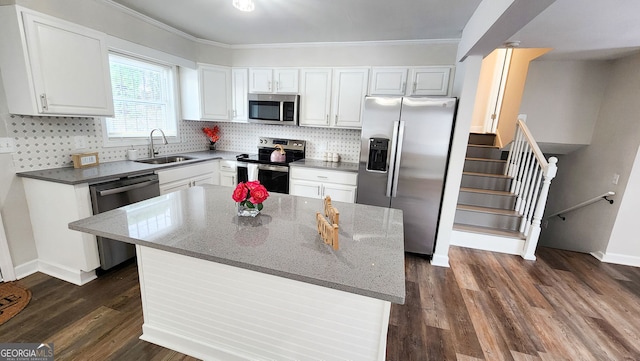 kitchen featuring white cabinets, decorative backsplash, dark stone counters, stainless steel appliances, and a sink